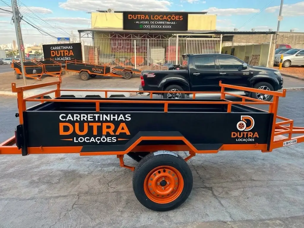 Carretinha Dutra Locações laranja e preta em frente à loja